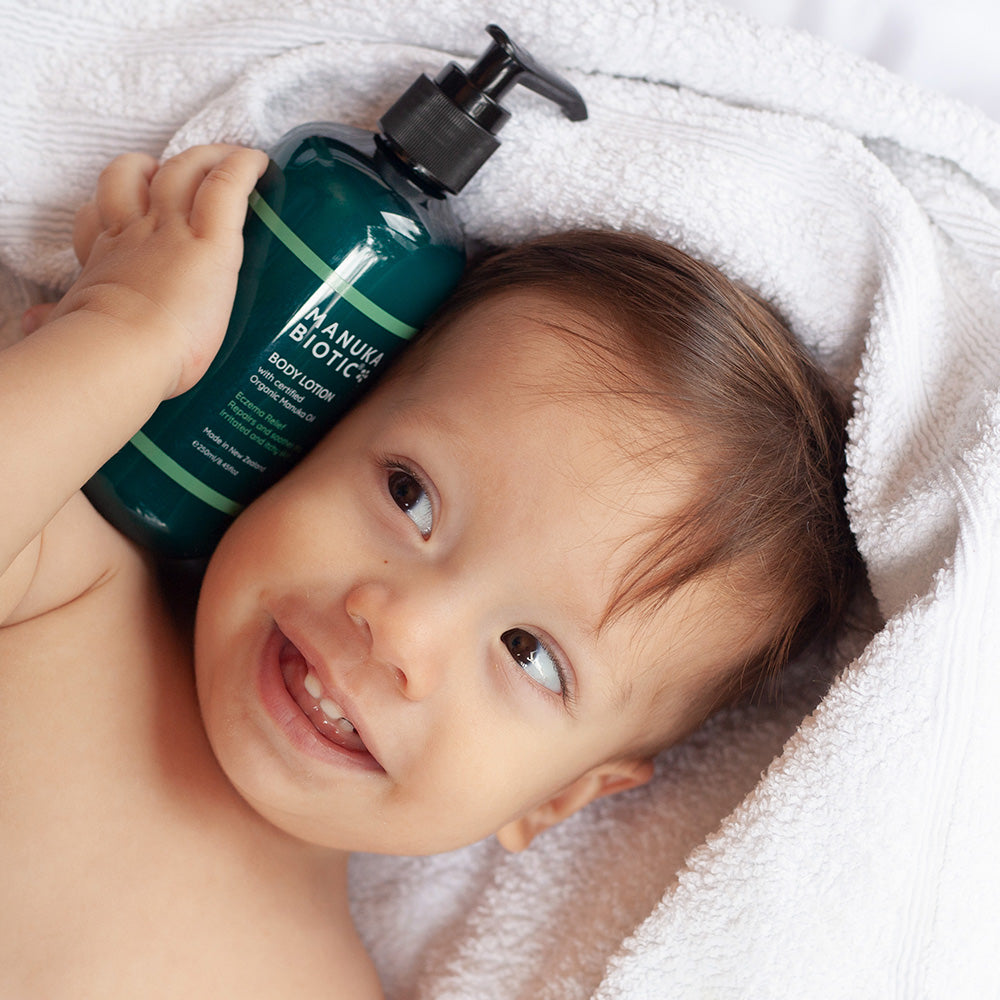  Baby smiling at a bottle of Manuka Biotic body lotion