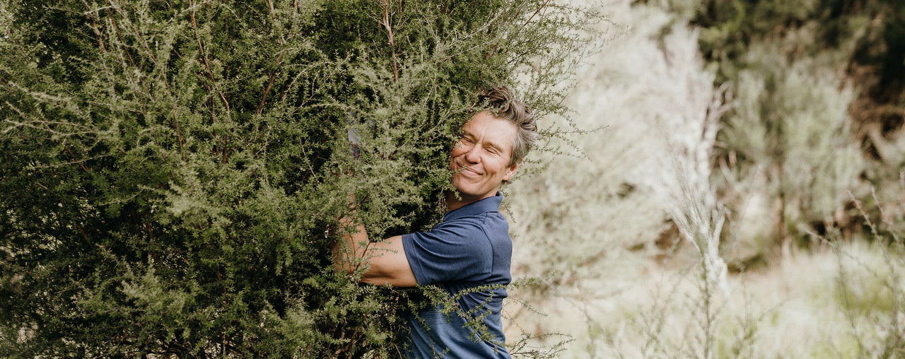  Tim Murray_Leslie with his eyes closed and smiling hugging a mānuka tree 