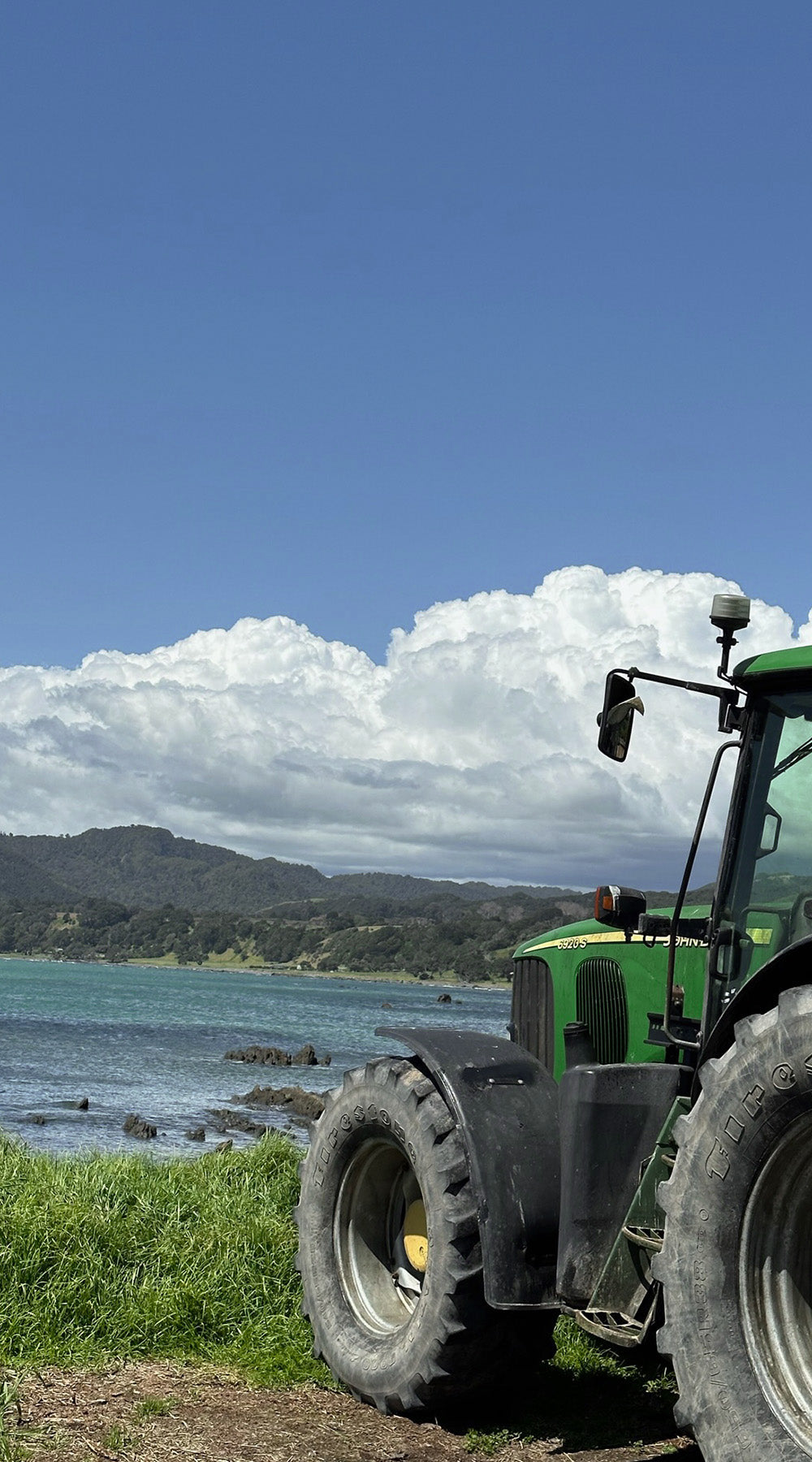  A tractor on a farm with the ocean in the distance