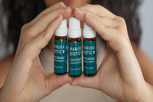  Lady holding three bottle of Manuka Oil to help treat fungal infections like athletes foot and nail infection