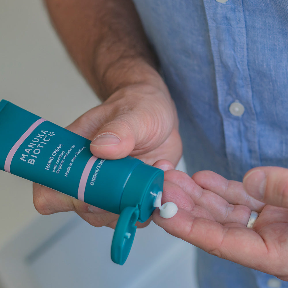  A man squeezing Manuka Biotic hand cream from a bottle