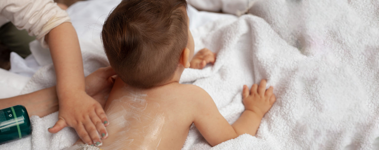  A hand rubbing Manuka Biotic lotion into the skin on the back of a baby