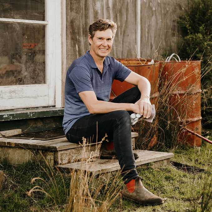  Tim Murray-Leslie sitting on wooden steps at his mānuka farm