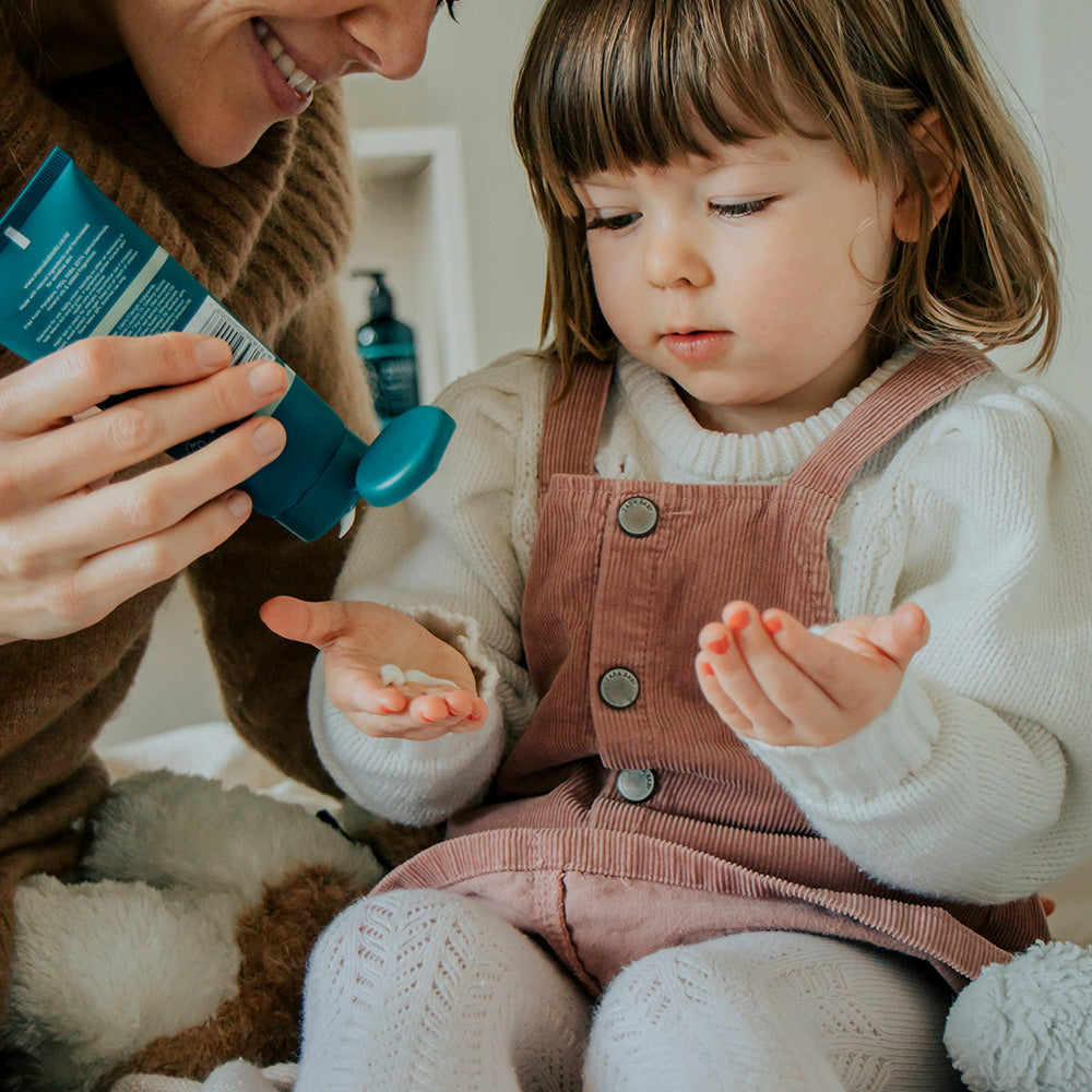  Woman squeezing Manuka Biotic lotion onto the hand of a little girl